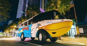 A yellow and white boat with 'RIDUCK' branding on a city street at night.