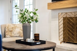 Ein runder Holztisch mit einer Blumenvase, einer Kerze und einer Tablett mit einem Buch und einer kleinen Schachtel.
