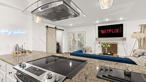 Et moderne køkken med et indbygget komfur, et stort fjernsyn der viser 'NETFLIX', og et neonskilt med teksten 'Tagesspiegel'.