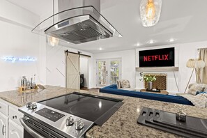 Eine moderne Küche mit Einbauherd, einem großen Fernseher, der 'NETFLIX' anzeigt, und einem Neonlicht mit der Aufschrift 'Tagesspiegel'.