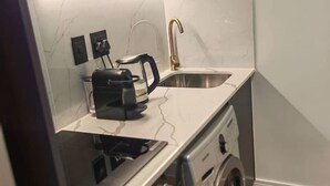 Uma cozinha compacta com fogão embutido, pia e máquina de lavar roupa.