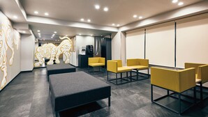 A modern waiting area with seating, a water dispenser, and a large screen wall.