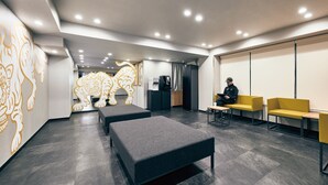 A modern waiting area with a reception desk, seating, and a decorative wall.