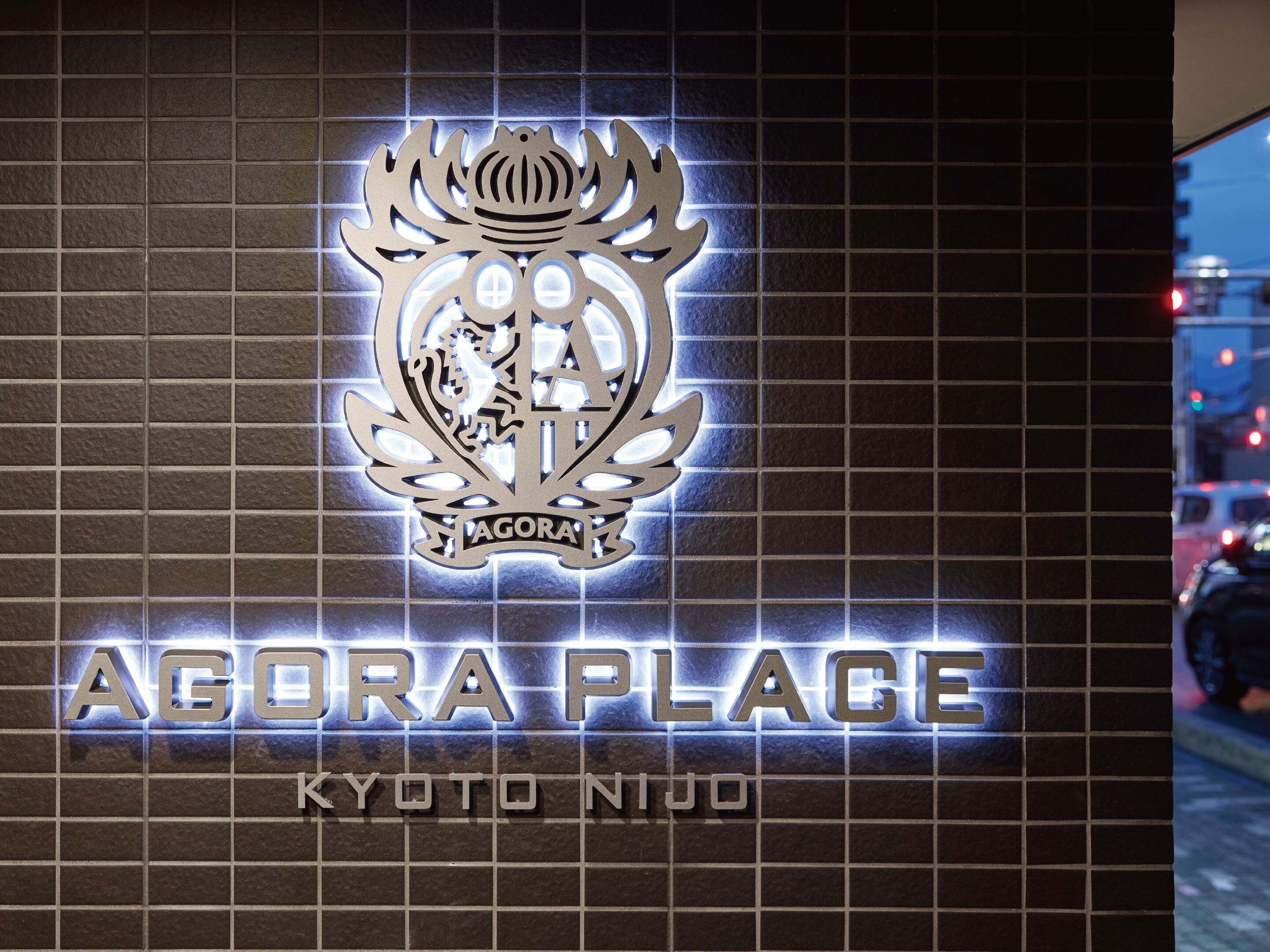 A sign with 'Agora Place' and 'Kyoto Nijo' text, featuring a crest emblem.