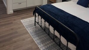 A bedroom with a bed, a bedside table with a lamp, a ceiling fan, a large mirror, and a wooden door. - The Dam Lakehouse B, Fishing & Boating Basecamp (Grand Coulee)