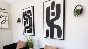 En stue med to sorte lænestole, et mønstret tæppe og abstrakt kunst på væggen.