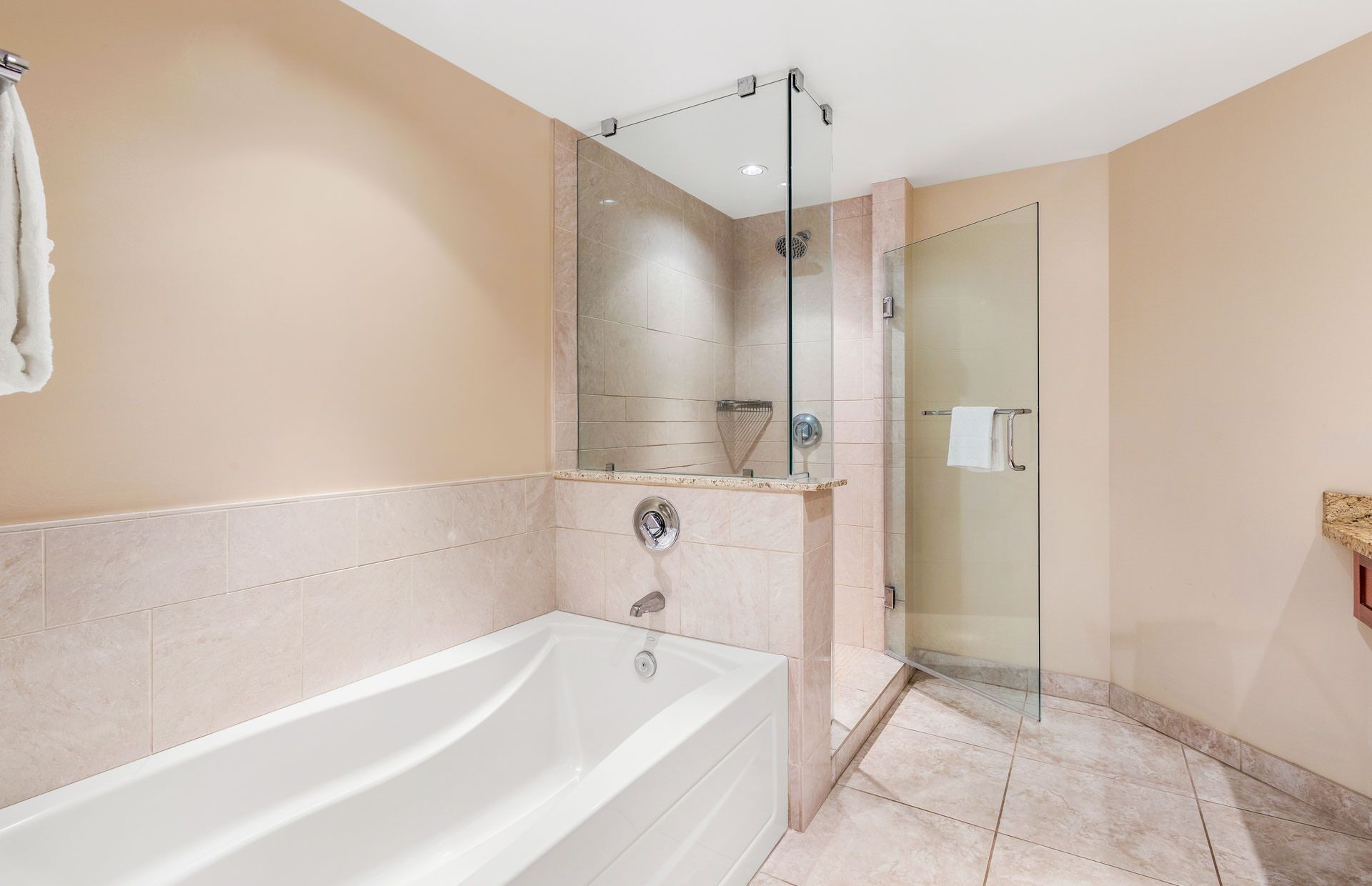A modern bathroom with a bathtub, a glass-enclosed shower, and a vanity with a mirror.