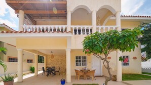 Um edifício de dois andares com um alpendre coberto, área de estar externa e um pequeno jardim.