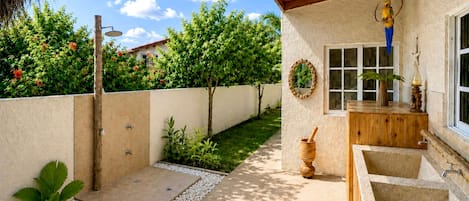 A covered outdoor area with a wooden bench, a small sink, and a window.