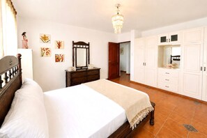 Een slaapkamer met een bed, een dressoir, een kledingkast en een kroonluchter.