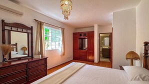 Quarto com uma cama grande, cômoda de madeira e um espelho.
