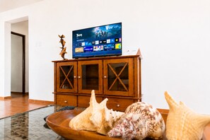 Een flatscreen televisie op een houten kast met een afstandsbediening ernaast.
