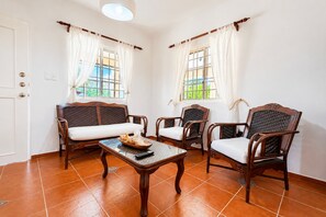 Une pièce comprenant deux canapés, deux fauteuils, une table basse et deux fenêtres avec des rideaux.