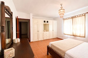 Une chambre à coucher avec un lit, une armoire, un miroir et un lustre.