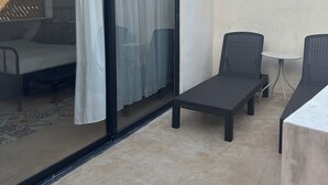 A balcony with a glass door, a bed, and two wicker chairs. - Casa Bélanger (Mérida)