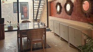 A modern kitchen with a dining area, featuring a large window, a ceiling fan, and decorative wall mirrors. - Casa Bélanger (Mérida)