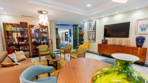 A modern living room with a sofa, chairs, a coffee table, a TV, and a bookshelf. - Hotel Sancho (Madrid)