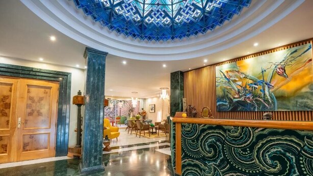 A lobby with a marble floor, a reception desk, and a large painting on the wall. - Hotel Sancho (Madrid)