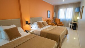 A hotel room with two beds, a desk, a chair, and a TV. - Hotel Sancho (Madrid)