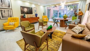 A modern living room with a sofa, chairs, a coffee table, and a dining area. - Hotel Sancho (Madrid)