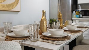 Une table à manger dressée avec des bols blancs, des verres transparents et des éléments décoratifs dorés.