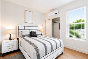 A bedroom with a bed, bedside tables, a wardrobe, and a window with blinds. - Premium Suite Steps from Convention Center (Hot Springs)