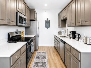 Een moderne keuken met roestvrijstalen apparatuur, een centraal kookeiland en een welkomstbord.