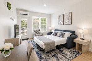 A modern bedroom with a bed, bedside tables, a chair, a desk, and a TV. - Modern New‑Build Suite • Hot Spring• Downtown (Hot Springs)