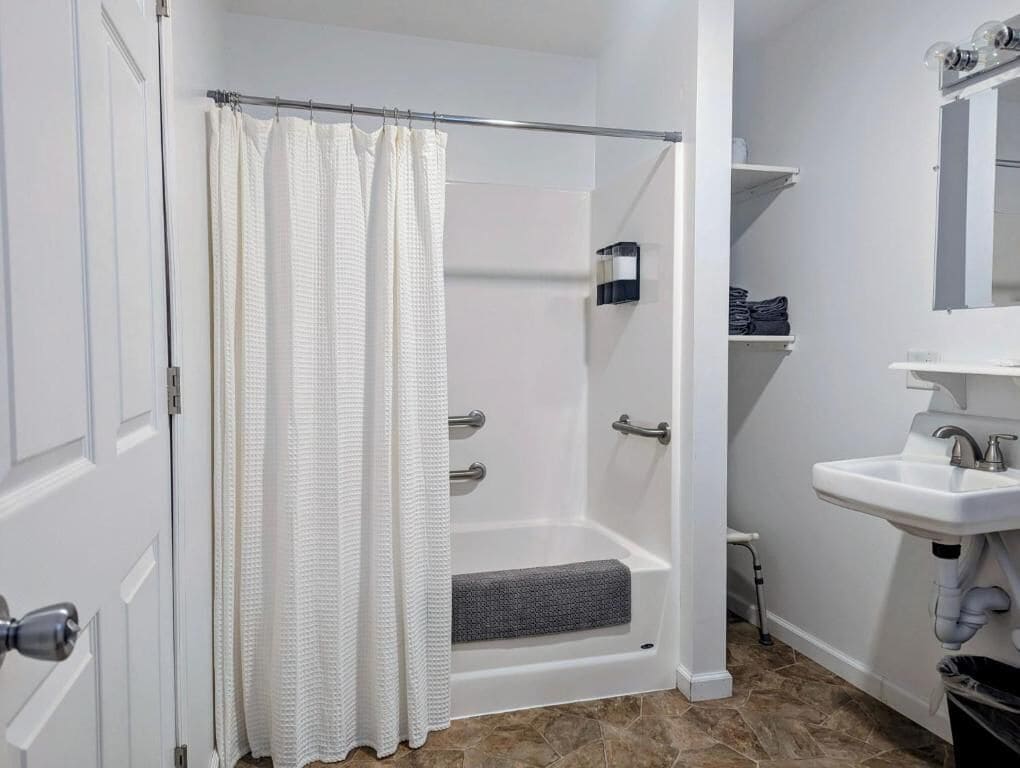 A bathroom with a shower, a sink, and a mirror.