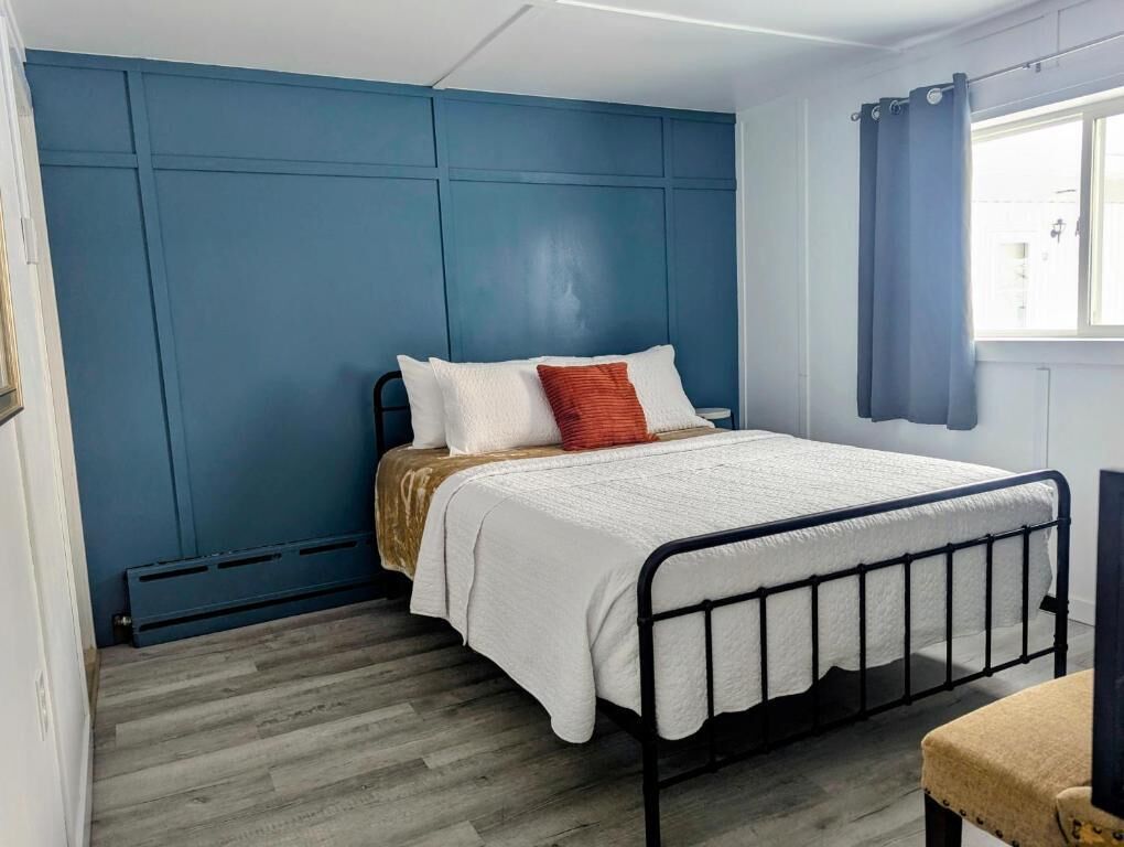 A bedroom with a bed, a window with curtains, and a radiator.