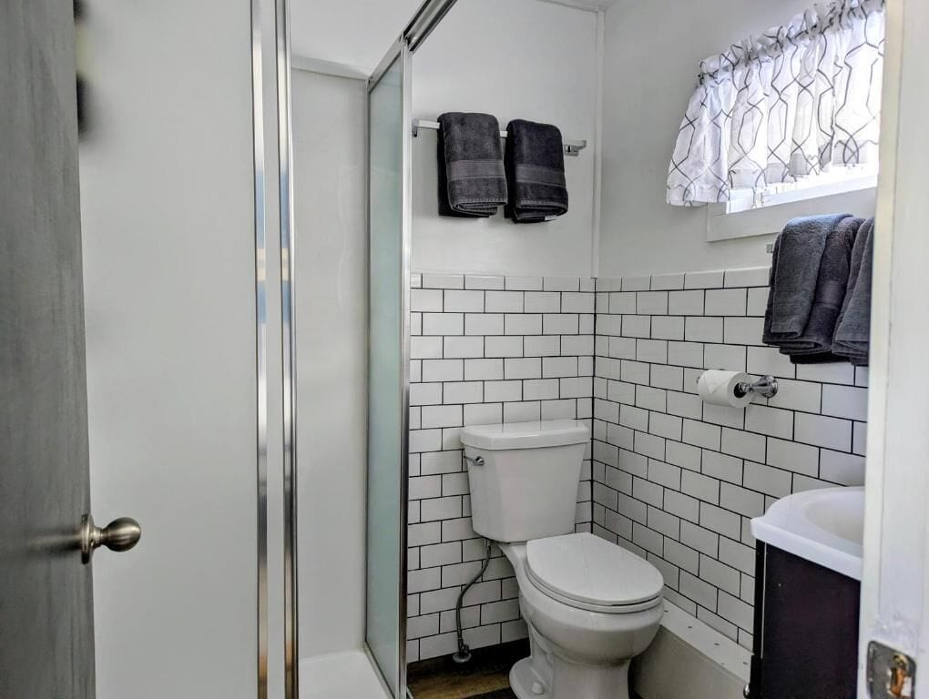 A bathroom with a white toilet, a sink, and a shower area.