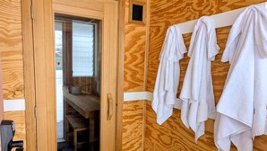 Un intérieur en bois avec une porte de sauna, un porte-serviettes avec des serviettes et une table en bois.