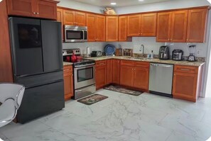 A kitchen with wooden cabinets, a refrigerator, a microwave, an oven, a dishwasher, and a granite countertop. - Villa hermosa (Key Largo)