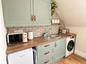 A compact kitchen with a microwave, kettle, sink, and washing machine. - Central Ayr Attic Apartment + Panoramic Town Views (Ayr)
