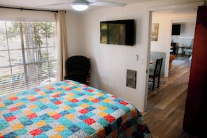 A bedroom with a bed, a chair, a television, and a window with blinds. - New Listing! Waterfront Toledo Bend Lake House w/ Private Dock - Sleeps 6 (Many)