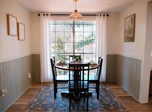 A dining area with a table set for four, a patterned rug, and a large window with curtains. - New Listing! Waterfront Toledo Bend Lake House w/ Private Dock - Sleeps 6 (Many)