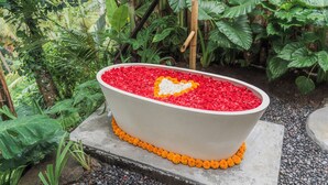 A large, white, oval-shaped water feature with red and white pebbles, surrounded by greenery. - LeLangit Eco Cabin (Sidemen)