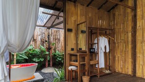A wooden room with a bathtub, wooden shelves, and a clothing rack. - LeLangit Eco Cabin (Sidemen)