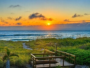 A wooden deck with railings overlooking a beach at sunset. - Oceanfront Quiet Beach + Rocket Launches (Cocoa Beach)