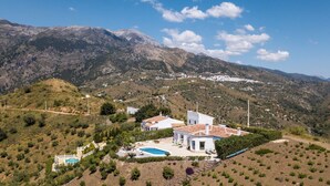 Eine Villa mit Schwimmbad, umgeben von Bergen und viel Grün.