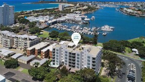 A marina with multiple boats docked, surrounded by residential buildings and a clear view of the ocean. - Rare 4BR Ground Floor Exclusive Apt (Mooloolaba)