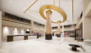 Un amplio vestíbulo de hotel con mostrador de recepción, zona de estar y una columna decorativa de gran tamaño.