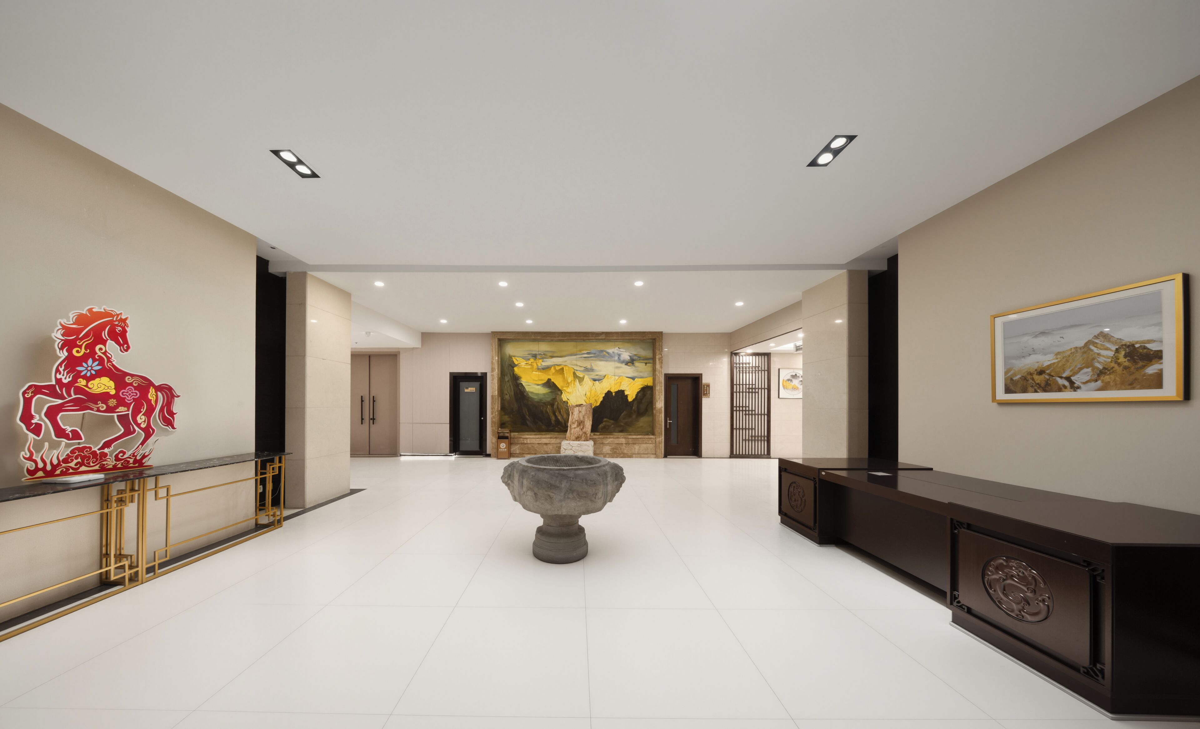 A spacious lobby with a large painting, a decorative horse sculpture, and a stone planter.