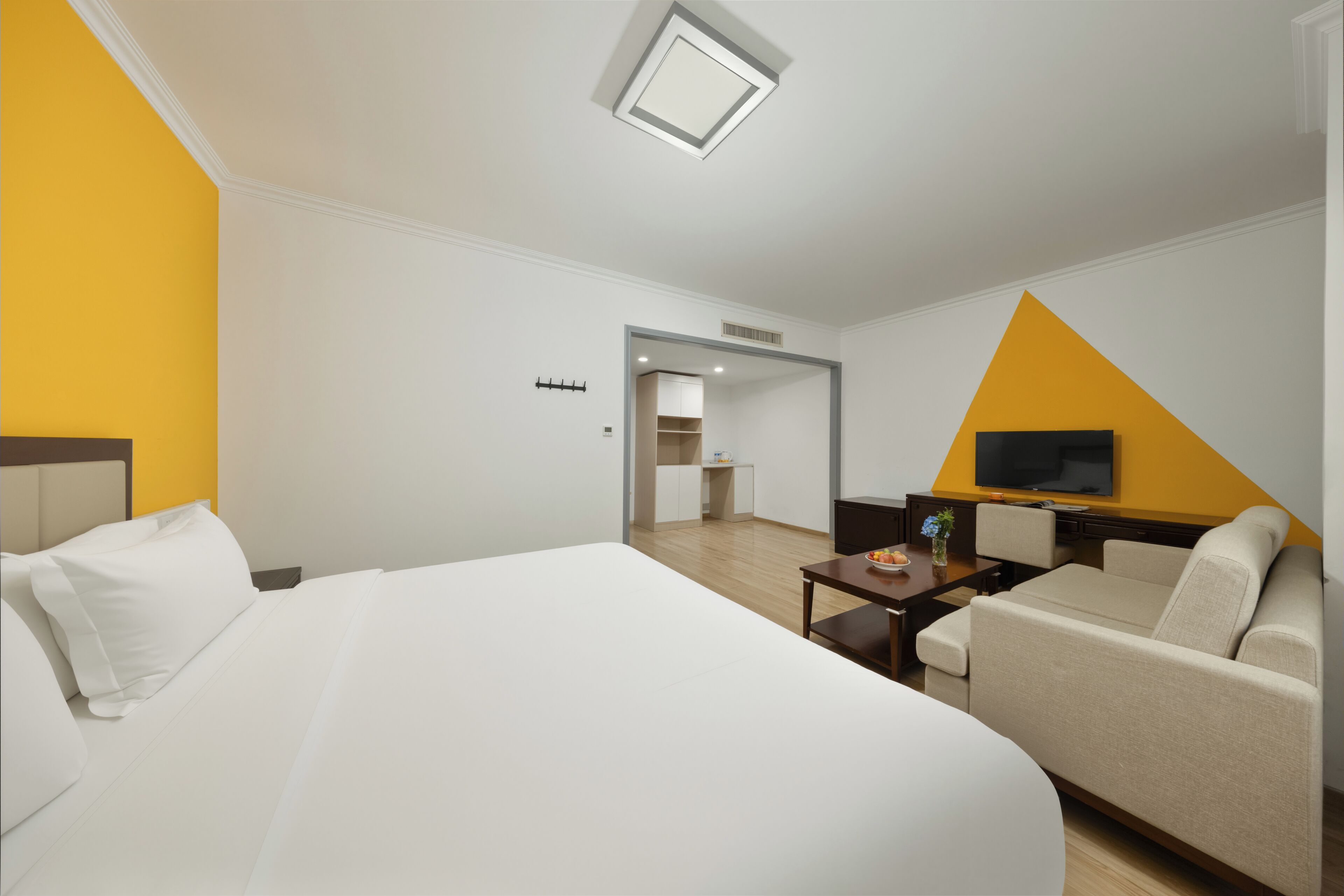 Habitación de hotel con cama, sofá, televisor, una mesita y kitchenette.