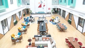 A spacious atrium with multiple seating areas, a central dining table, and a large wall with geometric patterns. - Golden Phoenix PEK Airport T3 Beijing  (Beijing)