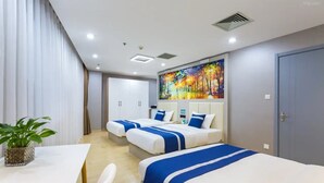 A hotel room with three beds, a dining area, a large painting on the wall, and a plant on the table. - Golden Phoenix PEK Airport T3 Beijing (Beijing)