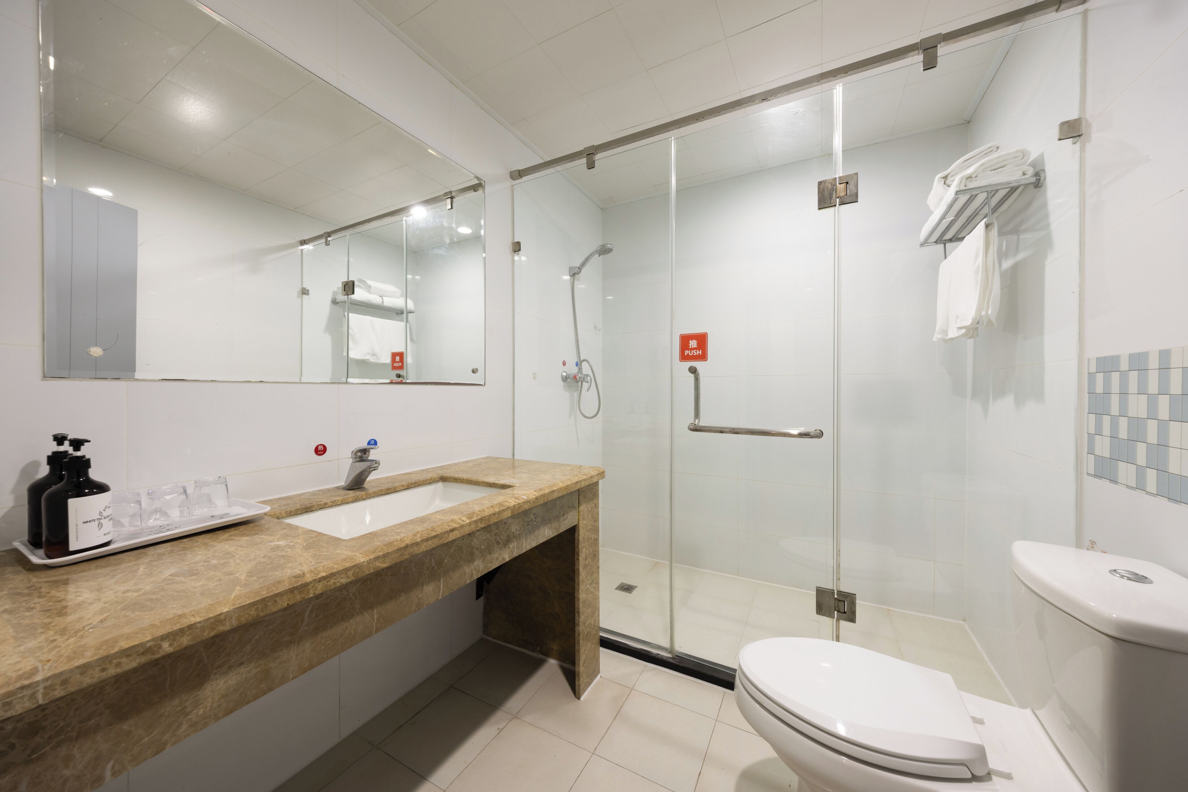 Un baño moderno con ducha de vidrio, lavamanos con encimera de mármol y retrete.