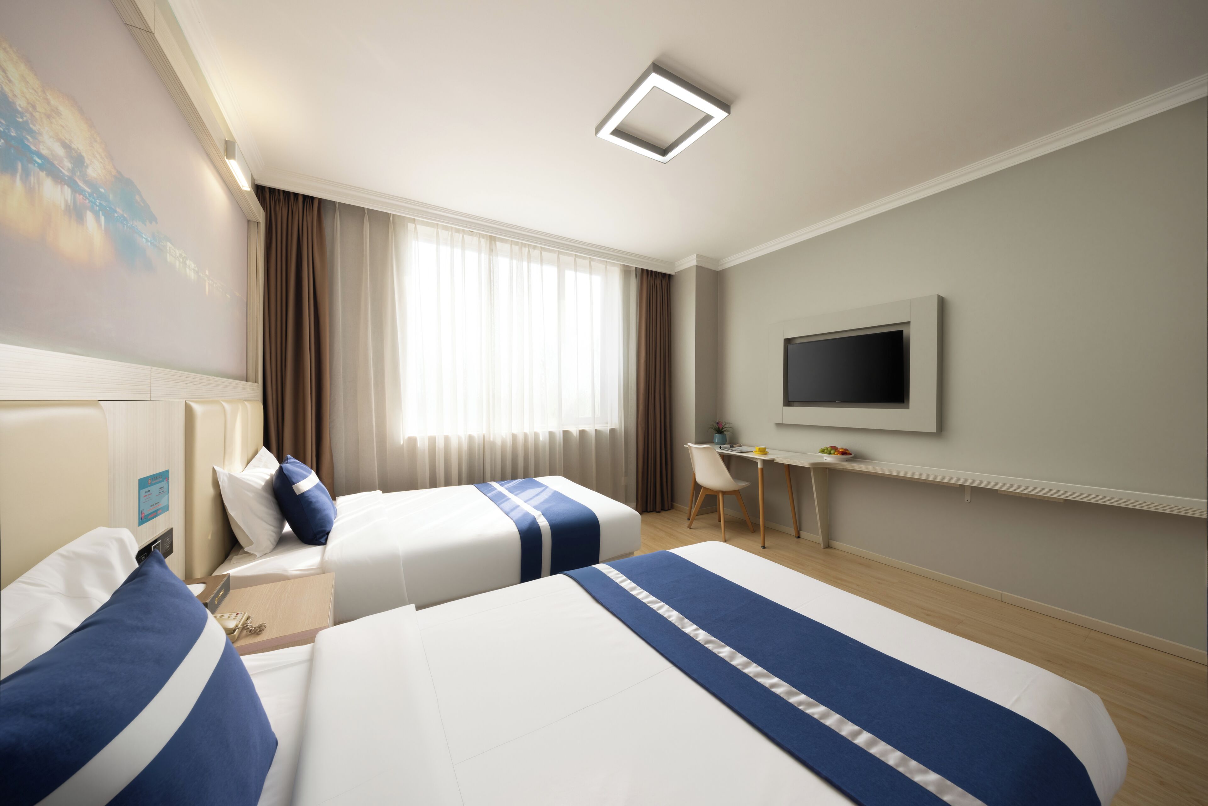 A hotel room with two beds, a desk, a chair, a TV, and a window with curtains.