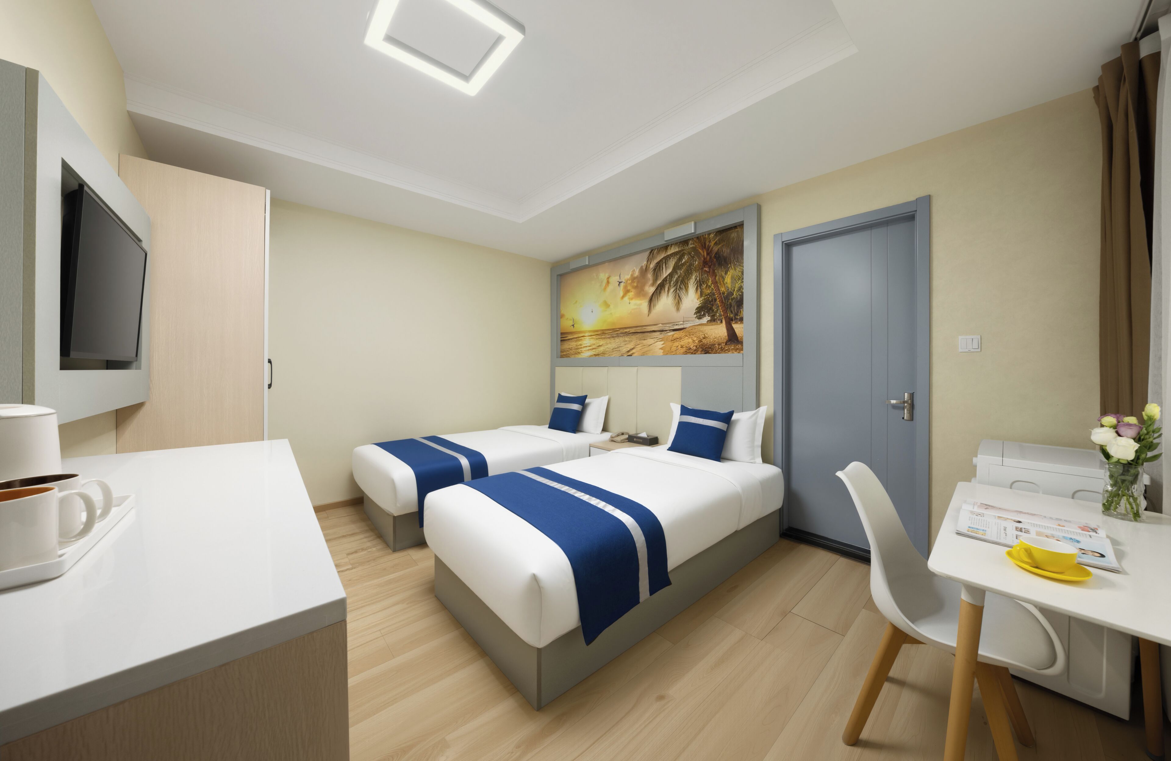 A hotel room with two beds, a desk, a chair, a TV, and a painting on the wall.