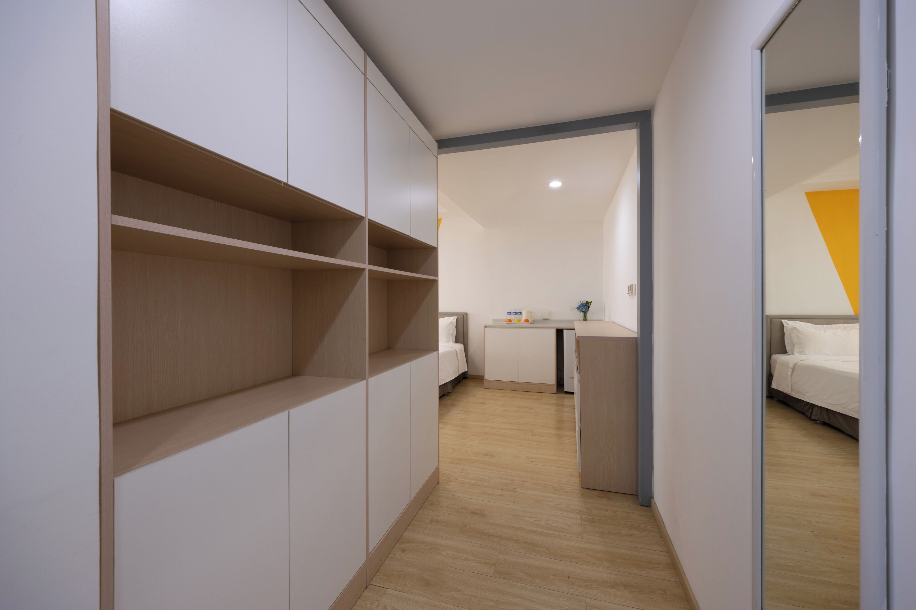 Ein Hotelzimmer mit Kleiderschrank, Schreibtisch, Bett und Blick auf den Flur.